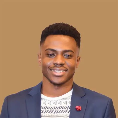 Smiling young Black man in a blue blazer with a red flower lapel pin.