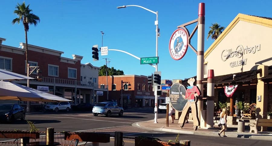 Sunny intersection in Old Town Scottsdale with western themed signs, storefronts, and a cowboy cutout.